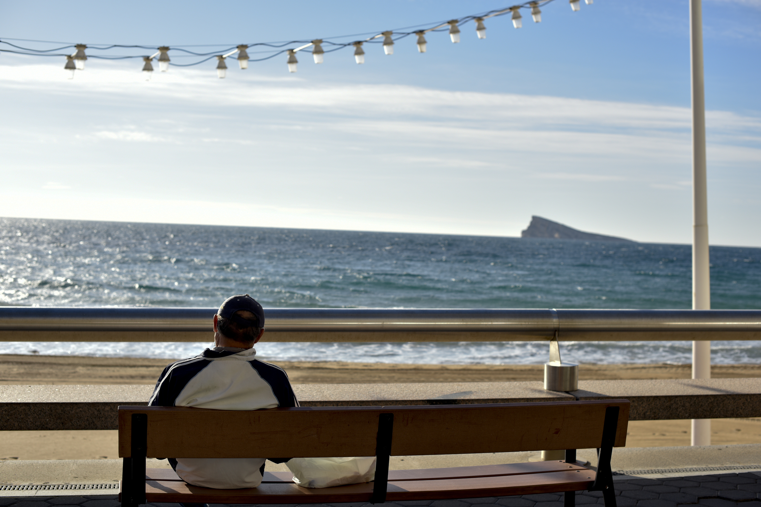 Un jubiloso sentado en un banco en la playa de Benidorm.