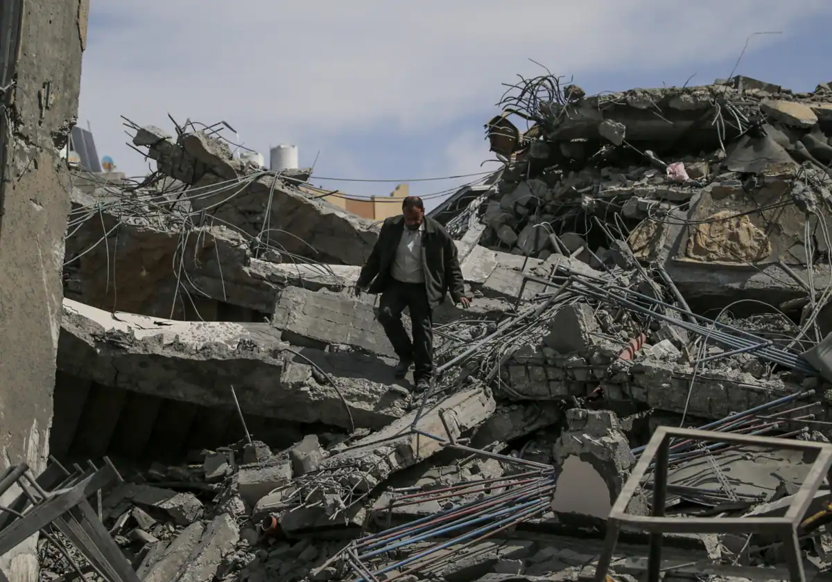 Un hombre camina entre las ruinas de un edificio bombardeado por Jan Yunis