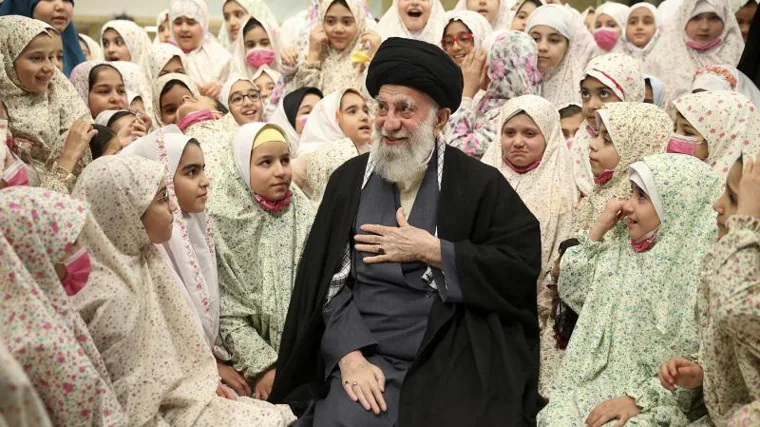 El Ayatolá Ali Jamenei lo demuestra hablando a niños iraníes antes de las oraciones durante una ceremonia.